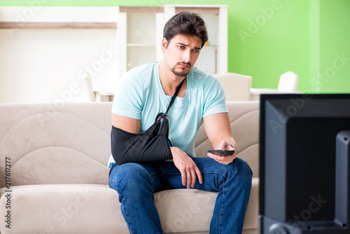 Arm injured man sitting on the sofa watching tv © Elnur