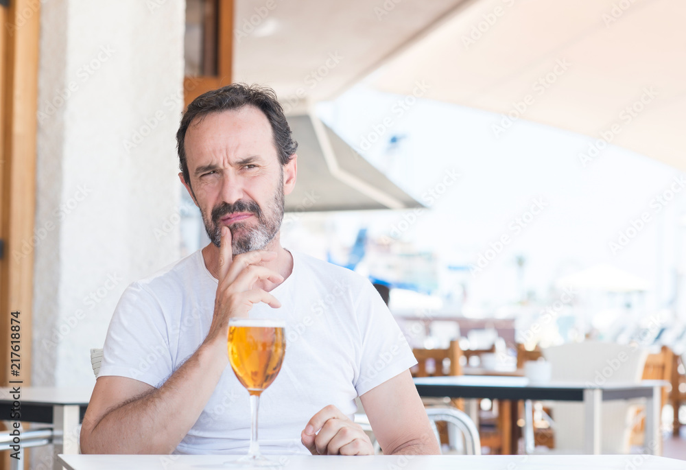 Handsome senior man drinking beer at restaurant serious face thinking about question, very confused idea Handsome senior man drinking beer at restaurant serious face thinking about question, very confused idea