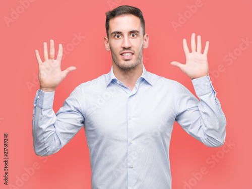 Handsome young businessman showing and pointing up with fingers number ten while smiling confident and happy. © Krakenimages.com