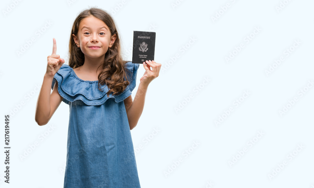 Brunette hispanic girl holding passport of United States of America surprised with an idea or question pointing finger with happy face, number one Brunette hispanic girl holding passport of United States of America surprised with an idea or question pointing finger with happy face, number one