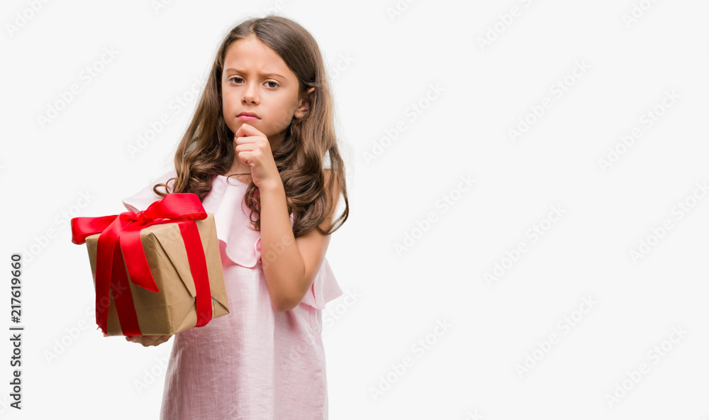 Brunette hispanic girl holding a gift serious face thinking about question, very confused idea Brunette hispanic girl holding a gift serious face thinking about question, very confused idea