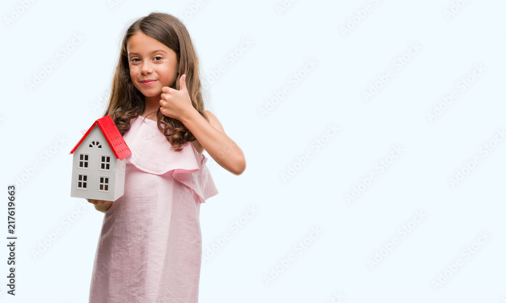 Brunette hispanic girl holding little house happy with big smile doing ok sign, thumb up with fingers, excellent sign Brunette hispanic girl holding little house happy with big smile doing ok sign, thumb up with fingers, excellent sign