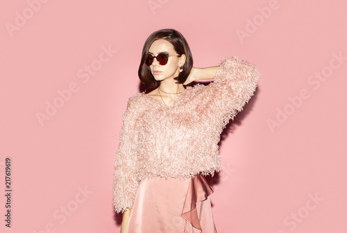 fashion woman in pink clothes and sunglasses looking away isolated on pink background
