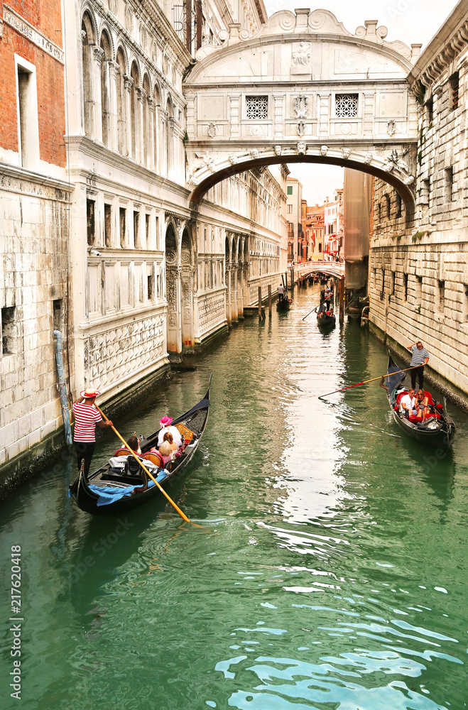 Gondolier carrying tourists in their gondola, by the bridge of sighs in venice, italy at sunset