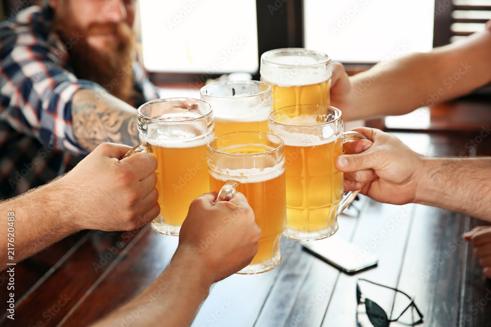 Friends clinking glasses with beer in pub Friends clinking glasses with beer in pub