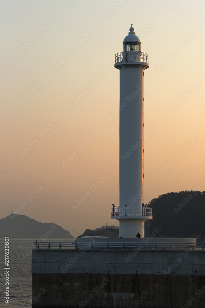 lighthouse at the exit of the port illuminated by the sunset