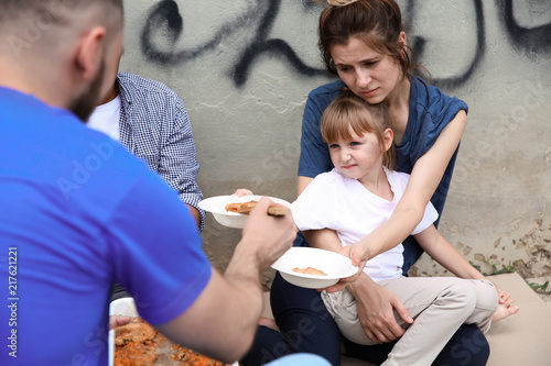 Poor people receiving food from volunteer outdoors