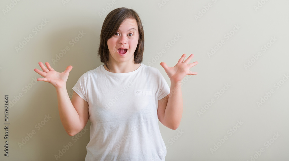 Down syndrome woman standing over wall celebrating crazy and amazed for success with arms raised and open eyes screaming excited. Winner concept Down syndrome woman standing over wall celebrating crazy and amazed for success with arms raised and open eyes screaming excited. Winner concept