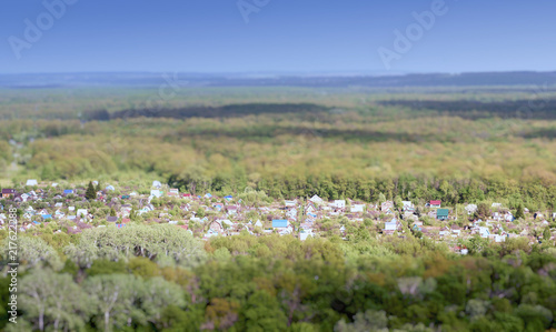 Colourful village homes and houses in the middle of a green lush forest using a tilt shift focus effect