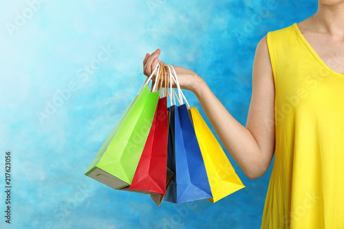 Woman holding paper shopping bags on color background