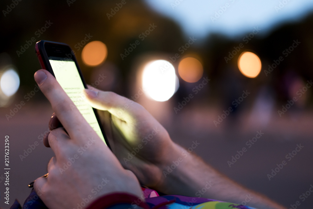 close up person hands holding phone and reading electronic book at night with bokeh close up person hands holding phone and reading electronic book at night with bokeh