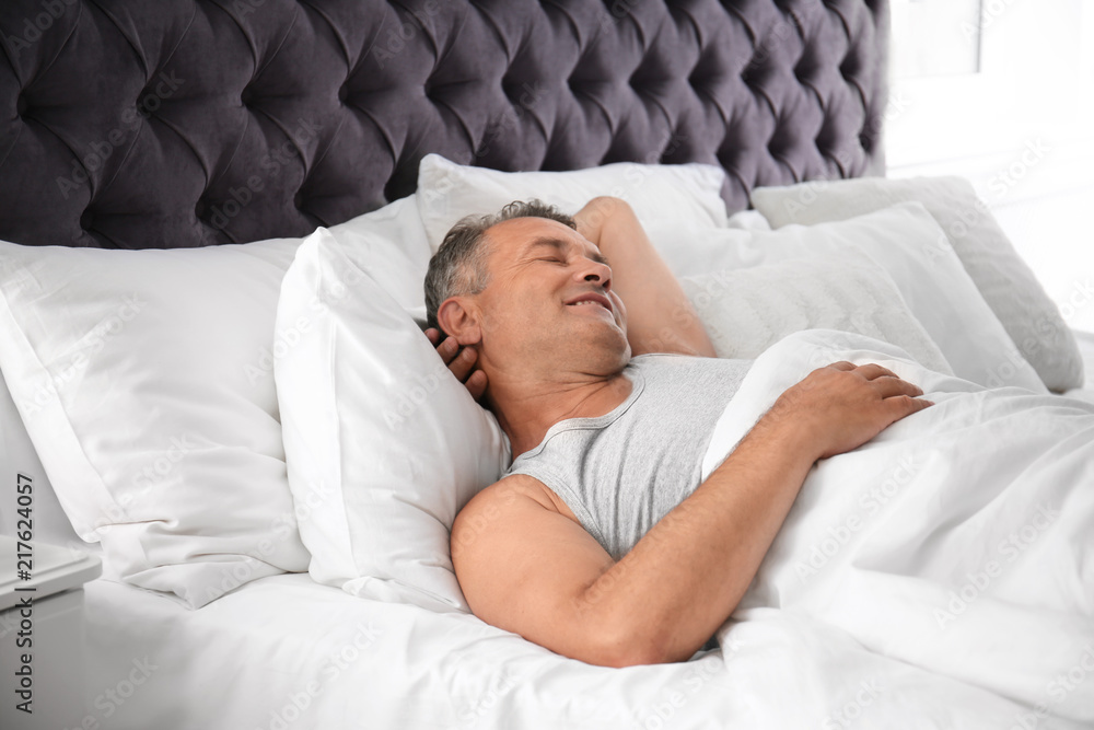 Man sleeping on comfortable pillow in bed at home Man sleeping on comfortable pillow in bed at home