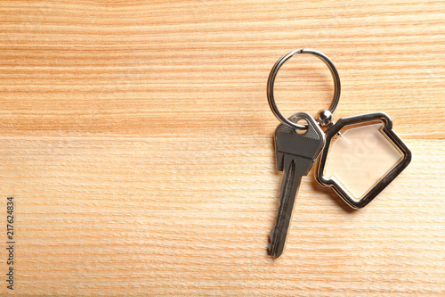 Key with trinket in shape of house on wooden background. Real estate agent services