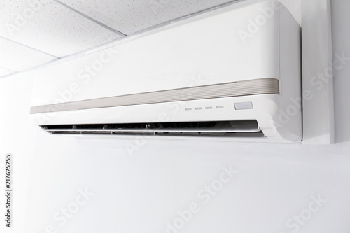 Modern air conditioner on white wall indoors, closeup view