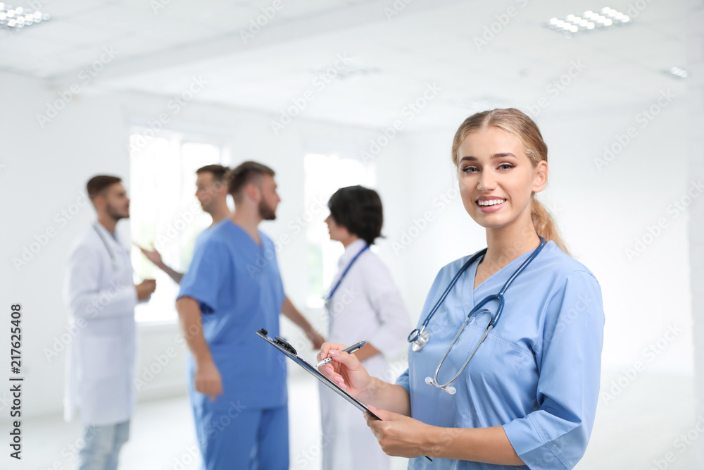Portrait of female doctor in uniform and her colleagues at workplace