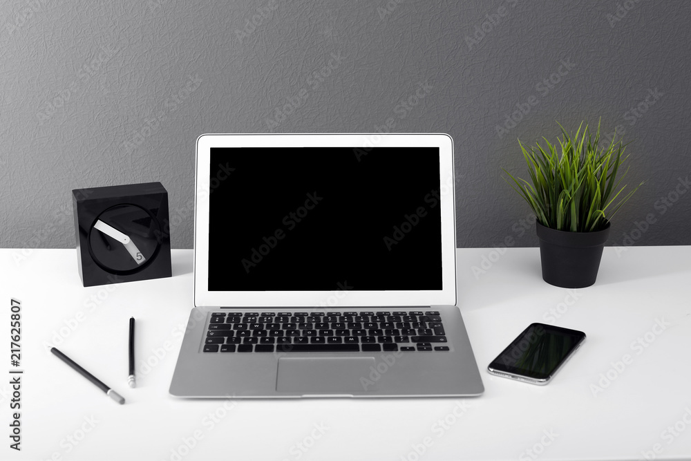 Fototapeta premium Modern laptop on table against gray wall. Mock up with space for text