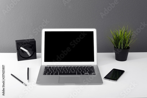 Modern laptop on table against gray wall. Mock up with space for text