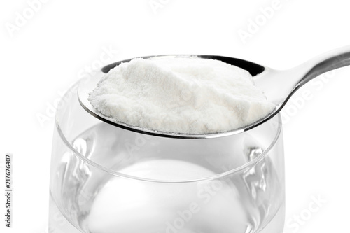 Spoon with baking soda over glass of water on white background