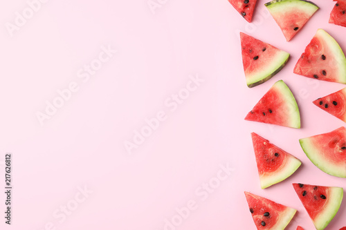 Slices of ripe watermelon on color background, top view with space for text