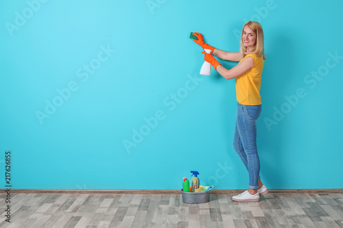 Woman in gloves cleaning color wall with sponge