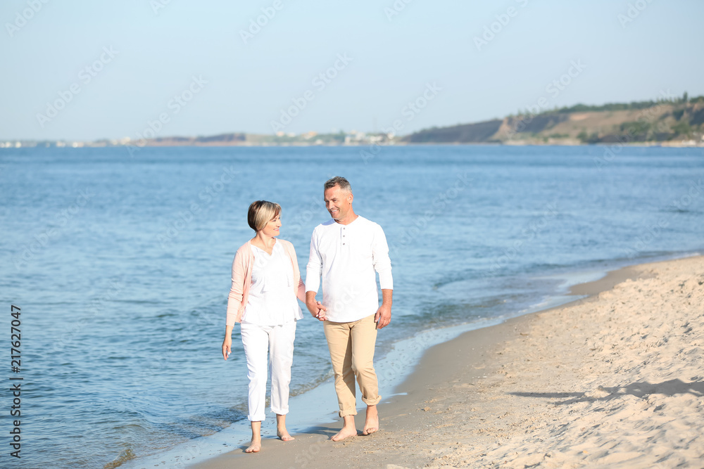 Happy mature couple walking at beach on sunny day Happy mature couple walking at beach on sunny day