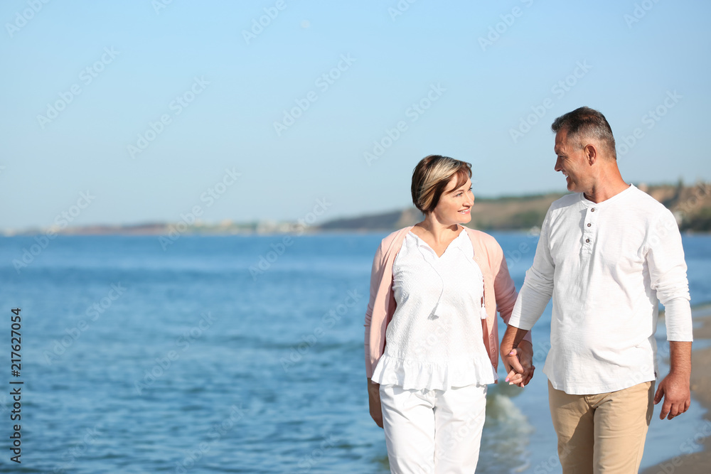Happy mature couple walking at beach on sunny day Happy mature couple walking at beach on sunny day