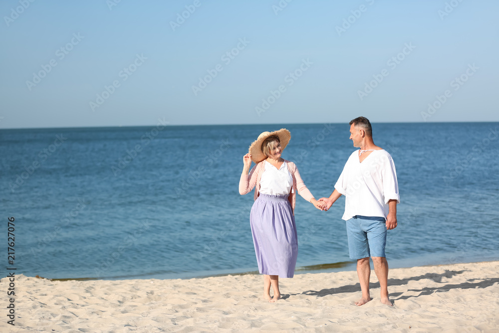 Happy mature couple holding hands at beach on sunny day Happy mature couple holding hands at beach on sunny day