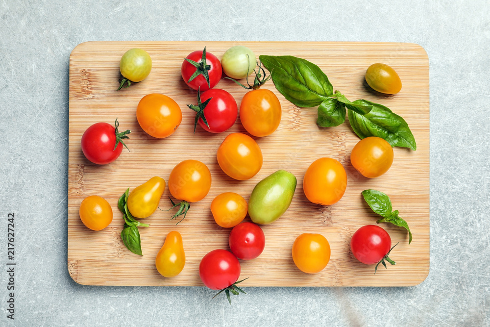 Wooden board with juicy tomatoes on grey background, top view Wooden board with juicy tomatoes on grey background, top view