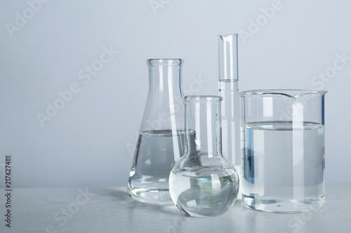 Laboratory glassware with liquid on table against gray background. Chemical analysis