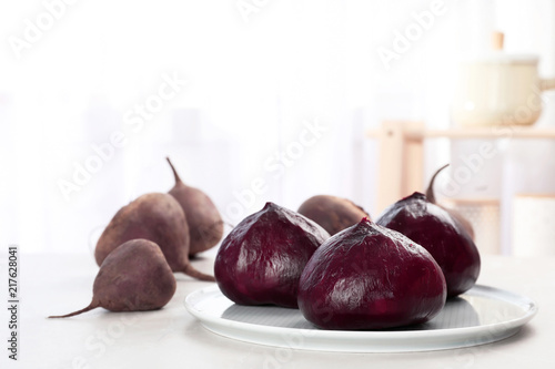 Plate with ripe peeled beets on table