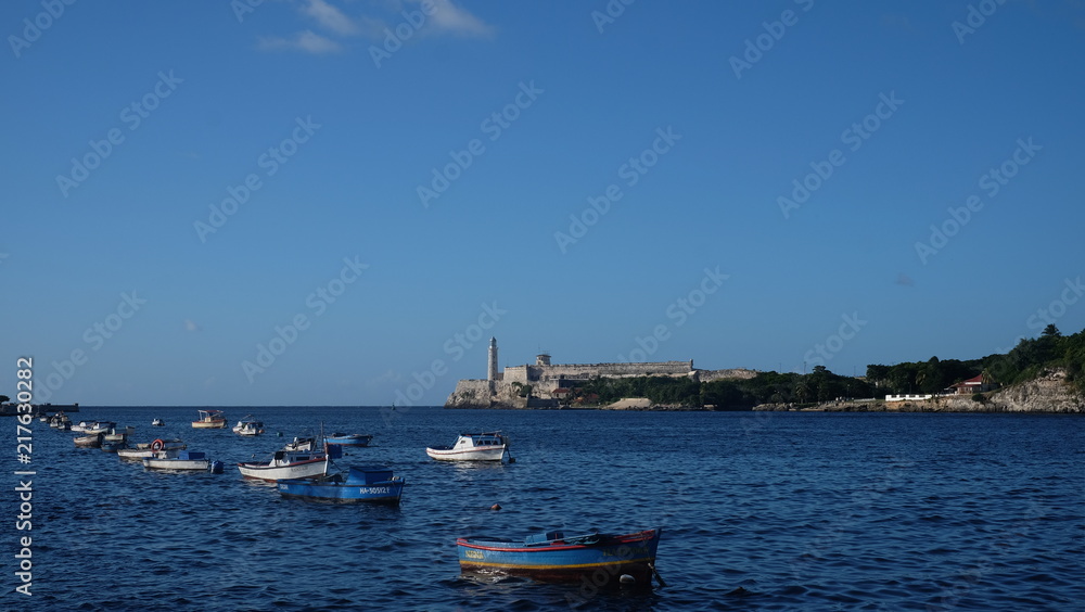 Fishing boats on blue ocean along Malecon roadway in Havana city, Cuba