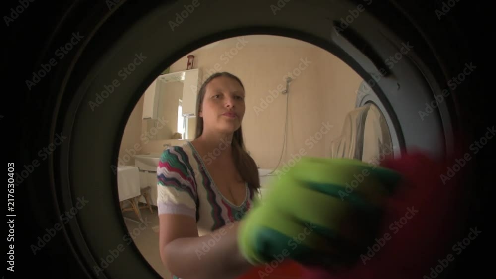 Young slender woman is washing off colored underwear. View from the drum in the washing machine