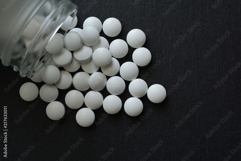 White pills on a black background
White pills on a black background