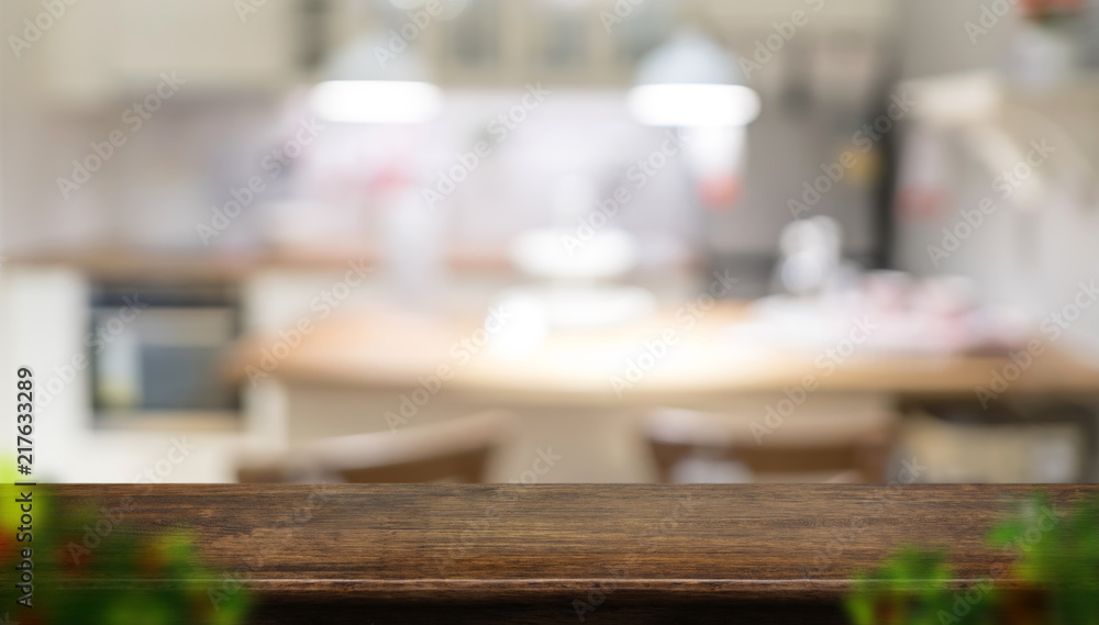 Empty dark brown wooden table top with blurred home kitchen with blur foreground leaf,Mock up template for display or montage of your design,Banner for advertise of product,panorama view.