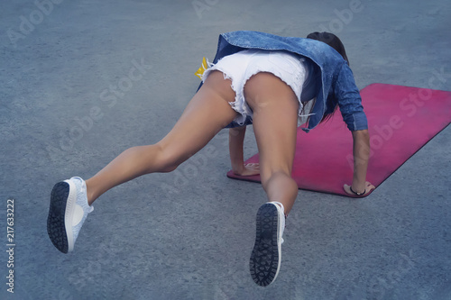 Profile view of a young woman doing push ups on a park photo