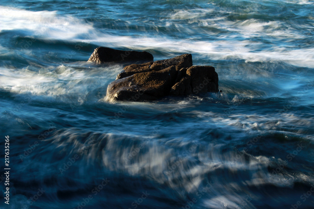Blurred ocean waves and rocks, background, abstract 