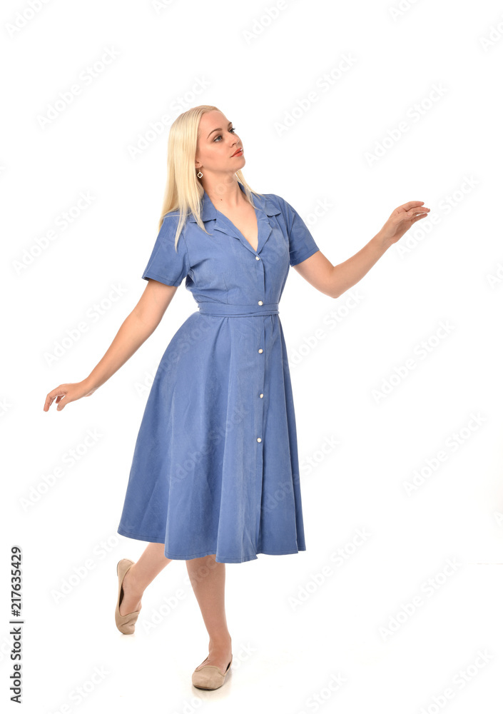 full length portrait of blonde girl wearing blue dress, standing pose. isolated on white studio background. full length portrait of blonde girl wearing blue dress, standing pose. isolated on white studio background.