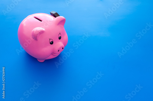 Piggy bank. Moneybox in shape of pig near hammer on blue background copy space