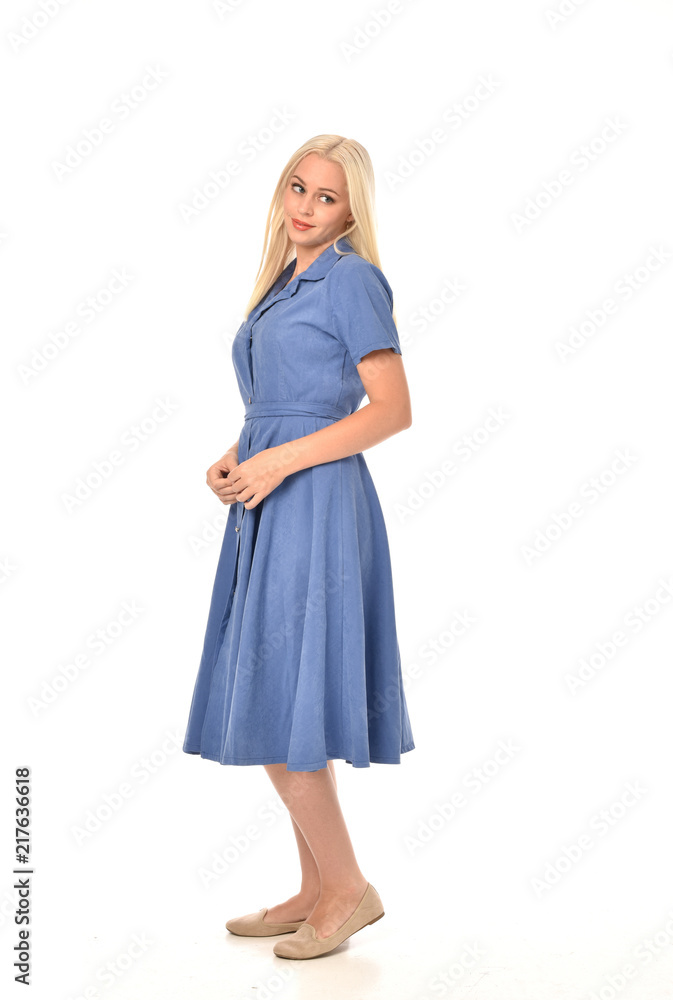 full length portrait of blonde girl wearing blue dress, standing pose. isolated on white studio background. full length portrait of blonde girl wearing blue dress, standing pose. isolated on white studio background.