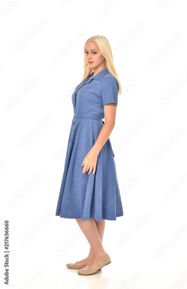 full length portrait of blonde girl wearing blue dress, standing pose. isolated on white studio background. full length portrait of blonde girl wearing blue dress, standing pose. isolated on white studio background.