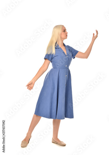 full length portrait of blonde girl wearing blue dress, standing pose. isolated on white studio background.