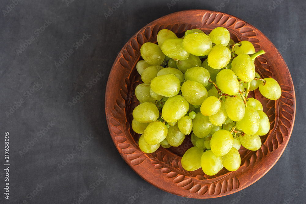 grape on brown plate on dark background with copy space
