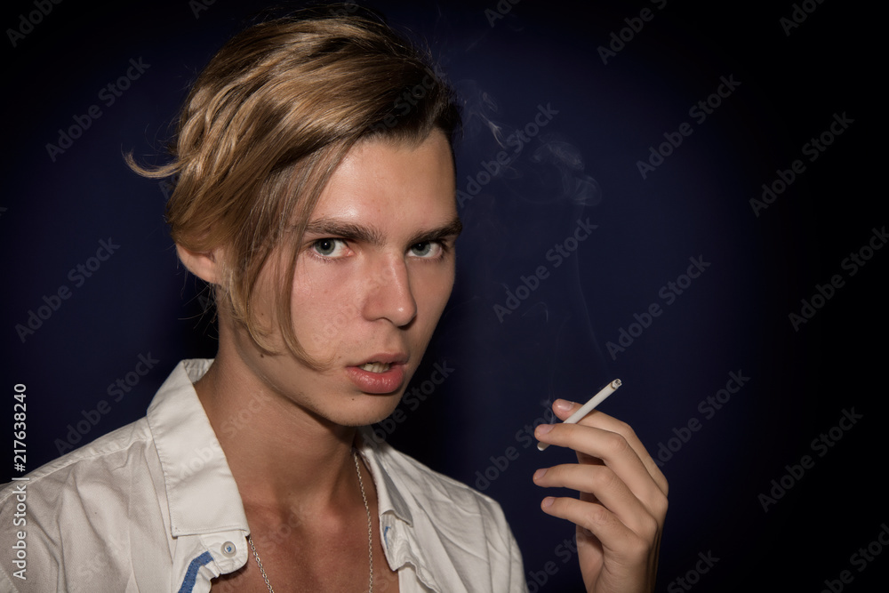Obraz premium A young guy smokes a cigarette. Bad habits.