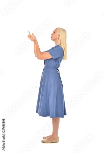 full length portrait of blonde girl wearing blue dress, standing pose. isolated on white studio background.