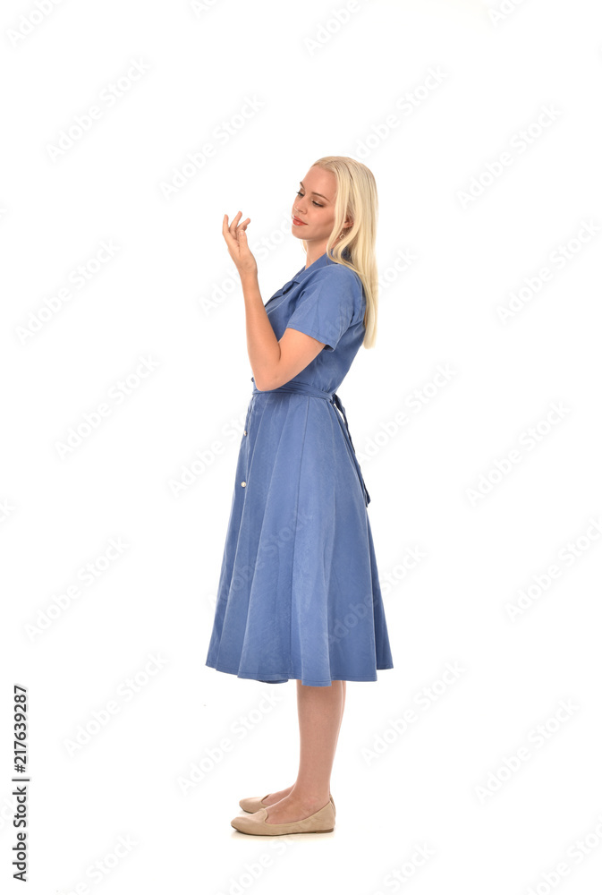 full length portrait of blonde girl wearing blue dress, standing pose. isolated on white studio background. full length portrait of blonde girl wearing blue dress, standing pose. isolated on white studio background.