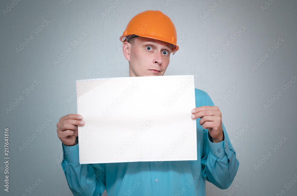 Serious builder construction worker is holding in hand a plan draft document isolated on gray background. Serious builder construction worker is holding in hand a plan draft document isolated on gray background.