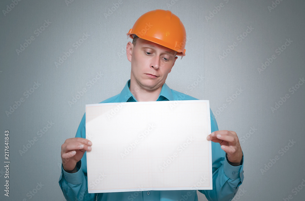 Serious builder construction worker is holding in hand a plan draft document isolated on gray background. Serious builder construction worker is holding in hand a plan draft document isolated on gray background.