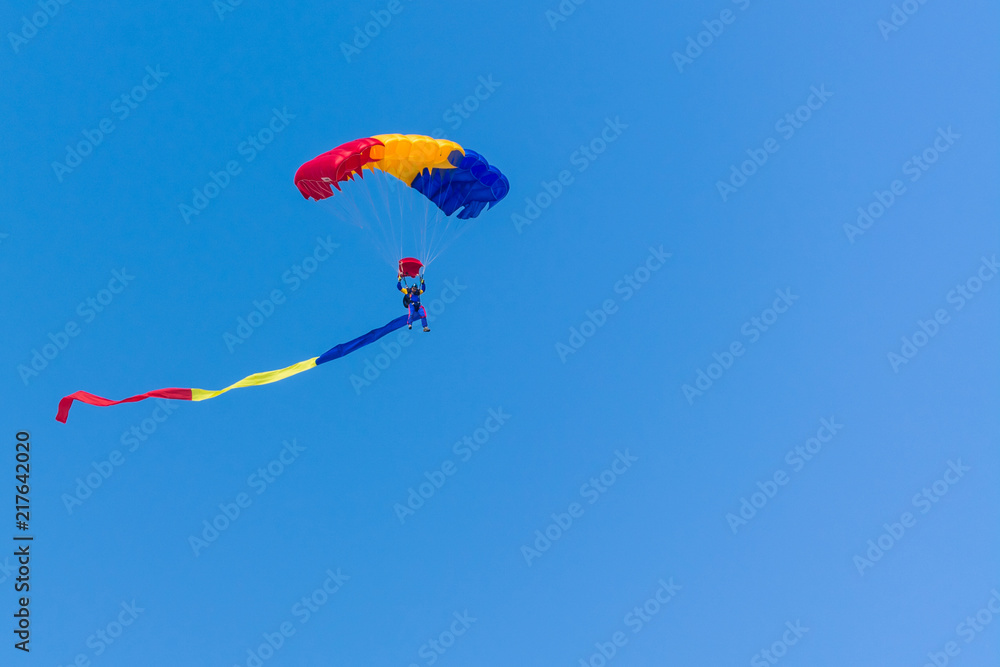A Parachute with Romanian Flag Colours on a Clean Blue Background A Parachute with Romanian Flag Colours on a Clean Blue Background