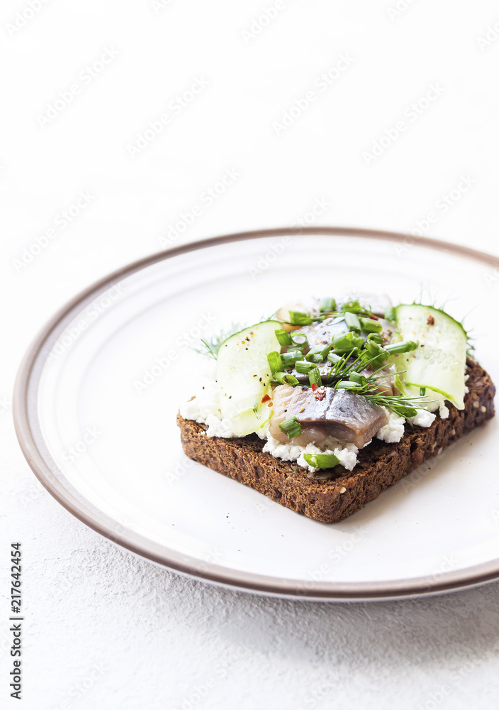 Sandwich with pieces of marinated herring with cream and dill. Selective focus.
