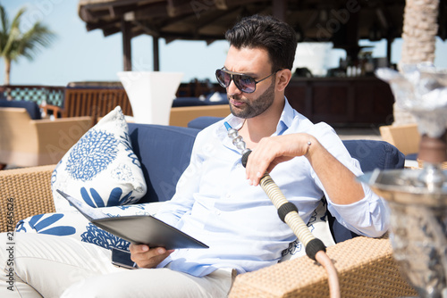 Expat man smoking sheesha and looking at restaurant menu.